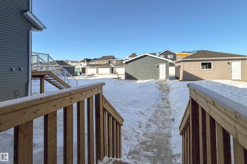 Yard covered in snow with a residential view, a wooden deck, and an outdoor structure - 112 Stonehouse Way, Leduc, AB - Outdoor