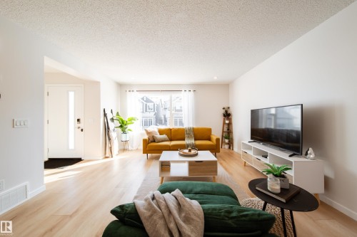 Living room with light wood finished floors and a textured ceiling - 112 Stonehouse Way, Leduc, AB - Indoor Photo Showing Living Room