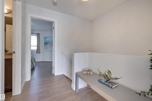 Corridor featuring wood finished floors, a textured ceiling, and an upstairs landing - 21 6032 38 Avenue, Edmonton, AB - Indoor