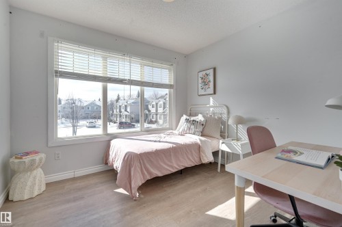 Bedroom featuring light wood finished floors, a textured ceiling, a desk, and a residential view - 21 6032 38 Avenue, Edmonton, AB - Indoor Photo Showing Bedroom
