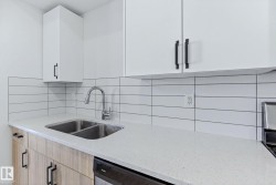 Kitchen with light stone counters, tasteful backsplash, stainless steel dishwasher, modern cabinets, and light wood finish cabinetry - 
