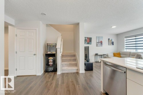 Kitchen featuring stainless steel dishwasher, dark wood-type flooring, a textured ceiling, open floor plan, and recessed lighting - 1323 South Creek Link, Stony Plain, AB - Indoor Photo Showing Kitchen