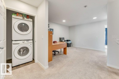 Laundry area featuring stacked washer / drying machine, an office area, recessed lighting, and light carpet - 1323 South Creek Link, Stony Plain, AB - Indoor Photo Showing Laundry Room