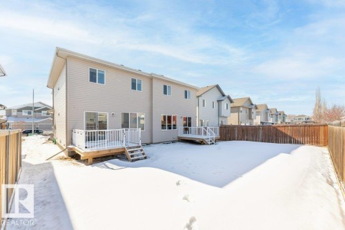Snow covered back of property featuring a fenced backyard, a residential view, and a wooden deck - 1323 South Creek Link, Stony Plain, AB - Outdoor