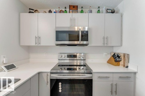 Kitchen with stainless steel appliances, light countertops, a textured ceiling, and white cabinets - 1323 South Creek Link, Stony Plain, AB - Indoor Photo Showing Kitchen