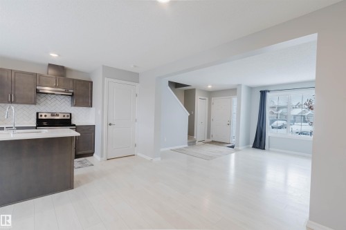 The property features a kitchen with dark cabinetry, white countertops, and a white subway tile backsplash, complete with a stainless steel sink and a black range - 326 Desrochers Boulevard, Edmonton, AB - Indoor Photo Showing Kitchen