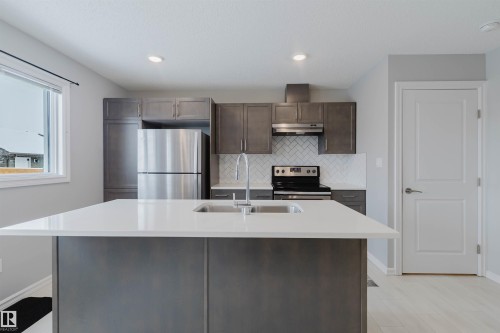 The kitchen features a spacious island with a double sink, stainless steel appliances, and sleek grey cabinetry - 326 Desrochers Boulevard, Edmonton, AB - Indoor Photo Showing Kitchen With Stainless Steel Kitchen With Double Sink With Upgraded Kitchen