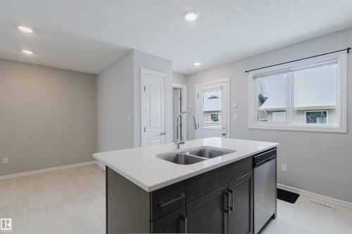 The kitchen features a functional island with a stainless steel double sink and faucet, complemented by a dishwasher - 326 Desrochers Boulevard, Edmonton, AB - Indoor Photo Showing Kitchen With Double Sink