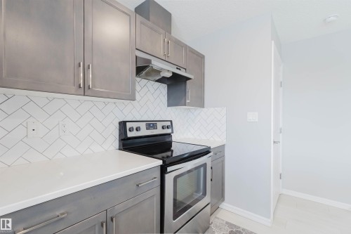 The kitchen features grey cabinetry, white countertops, and a white herringbone tile backsplash - 326 Desrochers Boulevard, Edmonton, AB - Indoor Photo Showing Kitchen With Stainless Steel Kitchen