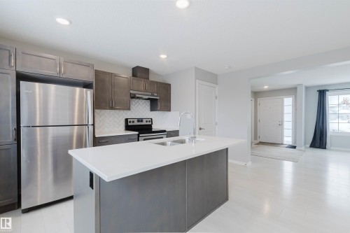 The kitchen features an island with a sink and a stainless steel faucet, and a stainless steel refrigerator - 326 Desrochers Boulevard, Edmonton, AB - Indoor Photo Showing Kitchen With Stainless Steel Kitchen With Upgraded Kitchen