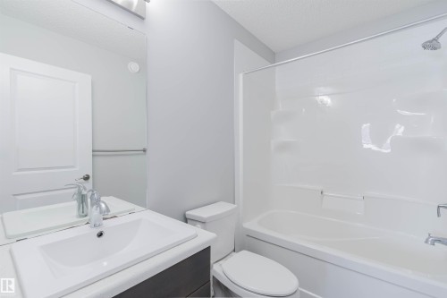 The bathroom features a modern vanity with a white sink, a mirror, and a toilet - 326 Desrochers Boulevard, Edmonton, AB - Indoor Photo Showing Bathroom