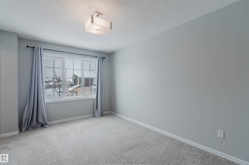 This room features light grey walls, grey carpet flooring, and a window with grey curtains - 326 Desrochers Boulevard, Edmonton, AB - Indoor