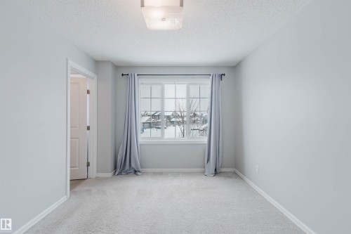 This room features light grey walls, a window with grey curtains, and light-colored carpet - 326 Desrochers Boulevard, Edmonton, AB - Indoor Photo Showing Other Room
