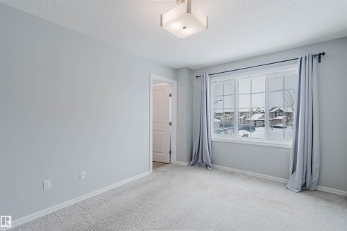This room features light grey carpeting, light grey walls, and a window with a view of the surrounding neighborhood - 326 Desrochers Boulevard, Edmonton, AB - Indoor Photo Showing Other Room