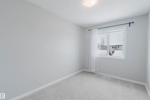 This room features light grey walls, light grey carpet flooring, a window with white trim, and a ceiling light fixture - 326 Desrochers Boulevard, Edmonton, AB - Indoor Photo Showing Other Room