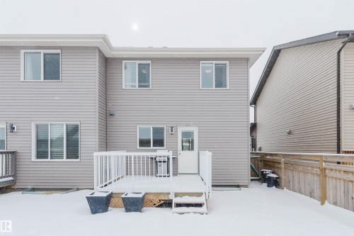 The property features a rear deck with white railings and stairs, providing access to the yard - 326 Desrochers Boulevard, Edmonton, AB - Outdoor With Exterior