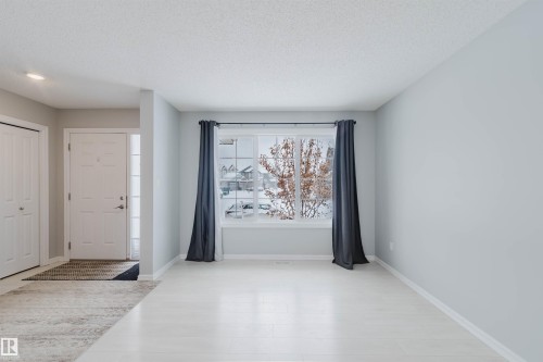 Living space featuring light-toned flooring and a large window with privacy drapes - 326 Desrochers Boulevard, Edmonton, AB - Indoor Photo Showing Other Room
