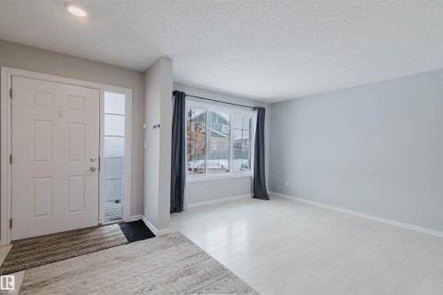 This entryway features a white panel door with an adjacent sidelight, light-toned walls, and a recessed ceiling light - 326 Desrochers Boulevard, Edmonton, AB - Indoor Photo Showing Other Room