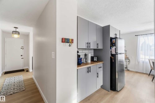 Kitchen with butcher block counters, light wood finished floors, freestanding refrigerator, gray cabinets, and a textured ceiling - 4615 49 Avenue, Redwater, AB - Indoor
