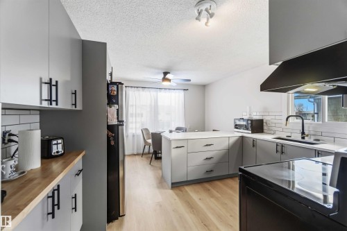 Kitchen with backsplash, black appliances, light wood finished floors, a textured ceiling, and gray cabinetry - 4615 49 Avenue, Redwater, AB - Indoor Photo Showing Kitchen With Upgraded Kitchen