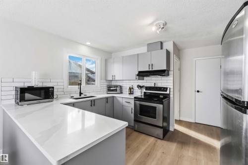 Kitchen with gray cabinets, stainless steel appliances, a peninsula, and light countertops - 4615 49 Avenue, Redwater, AB - Indoor Photo Showing Kitchen