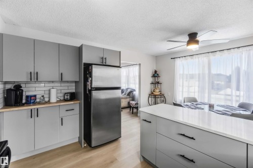 Kitchen with gray cabinetry, freestanding refrigerator, light wood finished floors, and a textured ceiling - 4615 49 Avenue, Redwater, AB - Indoor Photo Showing Kitchen