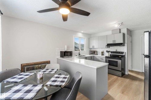 Kitchen featuring stainless steel appliances, a peninsula, light countertops, light wood-type flooring, and a textured ceiling - 4615 49 Avenue, Redwater, AB - Indoor
