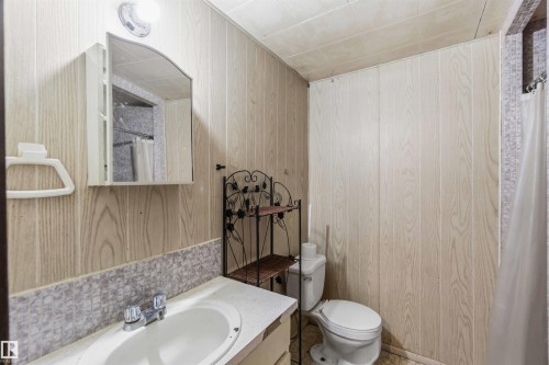 Bathroom featuring curtained shower, vanity, and wood walls - 4615 49 Avenue, Redwater, AB - Indoor Photo Showing Bathroom