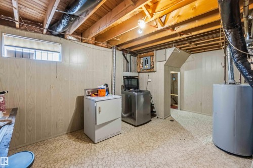Below grade area with wood walls, light flooring, water heater, washer / clothes dryer, and electric panel - 4615 49 Avenue, Redwater, AB - Indoor