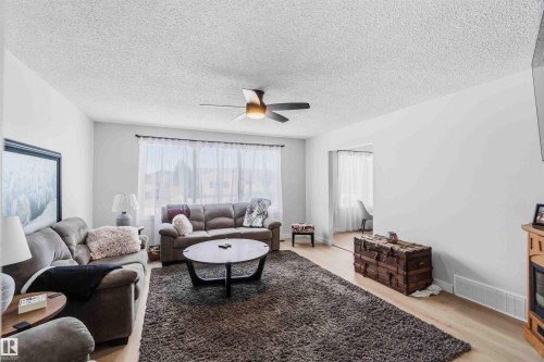 Living area with ceiling fan, light wood-style floors, and a textured ceiling - 4615 49 Avenue, Redwater, AB - Indoor Photo Showing Living Room With Fireplace