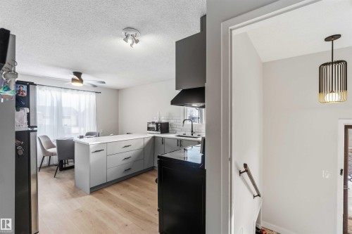 Kitchen featuring decorative backsplash, light wood finished floors, stainless steel appliances, gray cabinets, and light countertops - 4615 49 Avenue, Redwater, AB - Indoor