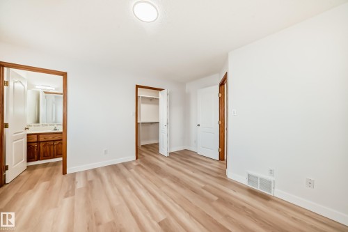 Unfurnished bedroom featuring a spacious closet, ensuite bath, and light wood-type flooring - 14063 128 Street, Edmonton, AB - Indoor Photo Showing Other Room