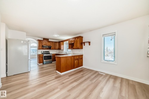 Kitchen with brown cabinets, light countertops, freestanding refrigerator, arched walkways, and stainless steel electric range oven - 14063 128 Street, Edmonton, AB - Indoor Photo Showing Kitchen