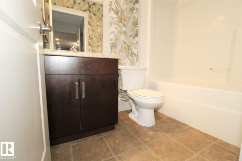 Bathroom with wallpapered walls, vanity, and bathtub / shower combination - 430 5515 7 Avenue, Edmonton, AB - Indoor Photo Showing Bathroom