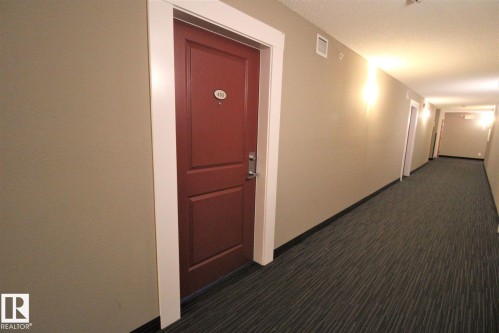 Hall featuring dark carpet and a textured ceiling - 430 5515 7 Avenue, Edmonton, AB - Indoor Photo Showing Other Room