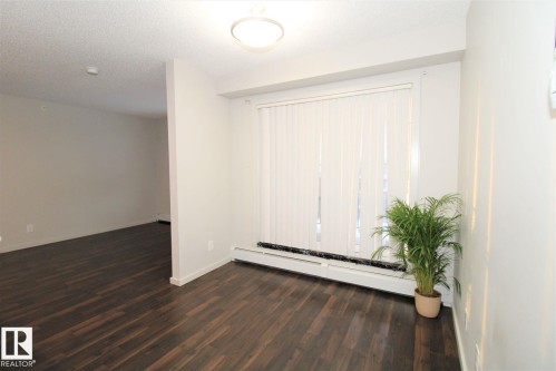 Spare room with a baseboard heating unit, dark wood finished floors, and a textured ceiling - 430 5515 7 Avenue, Edmonton, AB - Indoor Photo Showing Other Room
