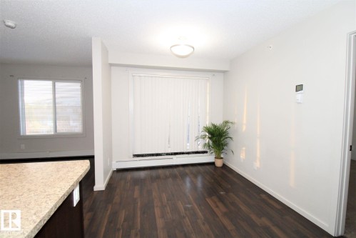 Unfurnished dining area with a baseboard radiator, dark wood-style flooring, and a textured ceiling - 430 5515 7 Avenue, Edmonton, AB - Indoor Photo Showing Other Room
