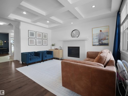 Living room with coffered ceiling, recessed lighting, wood finished floors, and a tiled fireplace - 3387 Parker Loop, Edmonton, AB - Indoor Photo Showing Other Room With Fireplace