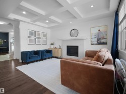 Living room with coffered ceiling, recessed lighting, wood finished floors, and a tiled fireplace - 