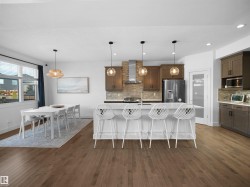 Kitchen with stainless steel appliances, an island with sink, a kitchen bar, hanging light fixtures, and tasteful backsplash - 
