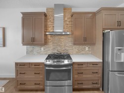 Kitchen with stainless steel appliances, tasteful backsplash, a textured ceiling, light wood finished floors, and light stone countertops - 