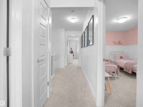 Hallway with light carpet, a textured ceiling, and a wainscoted wall - 3387 Parker Loop, Edmonton, AB - Indoor Photo Showing Other Room