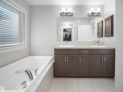 Full bathroom with double vanity, a garden tub, light tile patterned floors, and a spacious closet - 