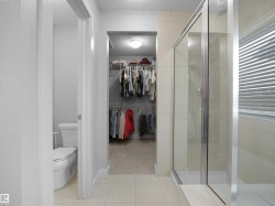 Bathroom with a textured ceiling, a walk in closet, a stall shower, light tile patterned floors, and light carpet - 