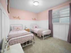 Bedroom with wainscoting, a decorative wall, a textured ceiling, light colored carpet, and radiator heating unit - 