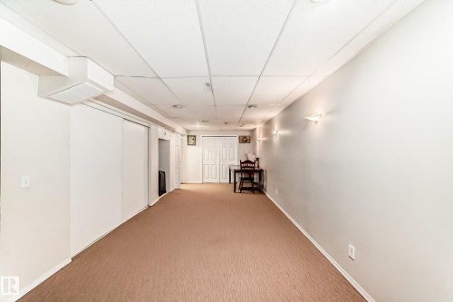 The property features a spacious room with light brown carpeting, white walls, and a drop ceiling with recessed lighting - 11532 9 Avenue, Edmonton, AB - Indoor Photo Showing Other Room