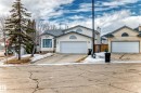 The property features an attached garage with a white door, a light-colored exterior, and a prominent arched window above the garage - 11532 9 Avenue, Edmonton, AB  - Outdoor With Facade 