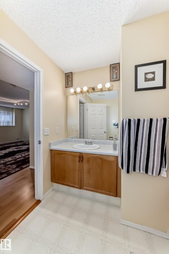 The bathroom features a vanity with a wood cabinet, a white countertop, and a white sink - 11532 9 Avenue, Edmonton, AB - Indoor Photo Showing Bathroom