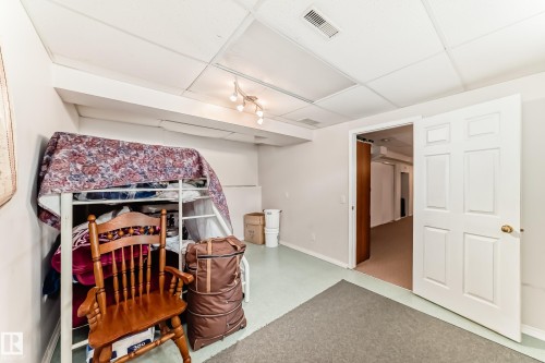 This room features a neutral color palette, a drop ceiling with recessed lighting, and a white paneled door - 11532 9 Avenue, Edmonton, AB - Indoor