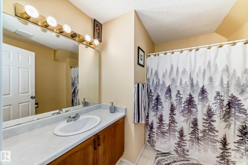 Bathroom featuring a vanity with a white countertop, an undermount sink, and a large mirror with overhead lighting - 11532 9 Avenue, Edmonton, AB - Indoor Photo Showing Bathroom